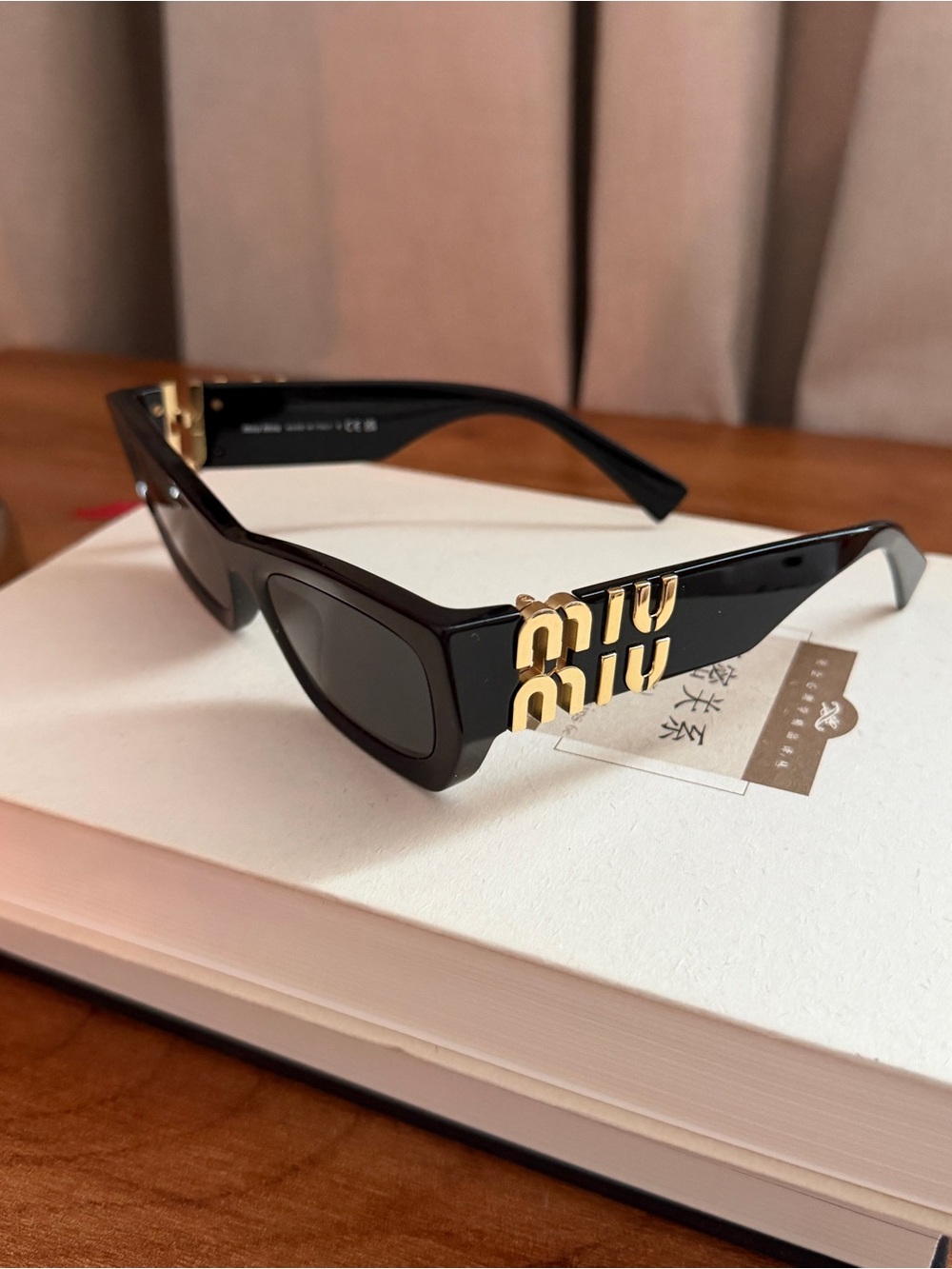 Miu Miu Black Cat-Eye Sunglasses with Gold Logo Accents - Picture 2 of 3